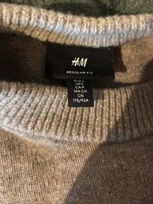 Beige stickad tröja från H&M - Snygg beige stickad tröja från H&M i regular fit. Tröjan har rund halsringning, långa ärmar och ribbade muddar vid ärmslut och nederkant. Perfekt för lager på lager och enkel att matcha med olika outfits.
