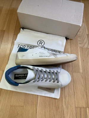 Golden goose - Säljer ett par Golden goose skor i storlek 43 med blå häl. Lådan, dustbagen och certifieringskortet följer med. Skick 10/10. Fraktar snabbt och skriv om ni undrar något 