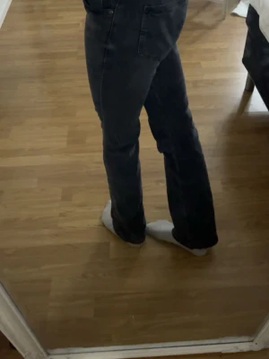 Svarta bootcut jeans från Lee - Säljer ett par svarta bootcut jeans från Lee med klassisk femficksmodell och mellan hög midja . Jeansen har en snygg tvätt och är tillverkade i ett mjukt denimtyg som sitter skönt. Perfekta för dig som gillar en tidlös och avslappnad stil.