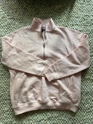 Ljusrosa quarter zip  - Ljusrosa sweatshirt från Asos med halv dragkedja och hög krage. Tröjan har två fickor framtill och diskret broderad logga på bröstet. Storlek xs/s endast använd en gång 