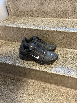 Nike TN UTILITY - Säljer ett par Nike Air Max Plus Tn sneakers i svart mesh med vita detaljer och Tn-logo på hälen. Skorna har en sportig design med synlig Air-dämpning och coola reflexdetaljer. Perfekt för dig som gillar streetstyle och vill ha något bekvämt och snyggt.