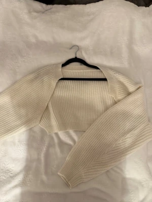 Vit cropped stickad bolero - Trendig vit stickad bolero. Kort, croppad modell.