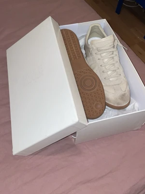 Manson margielas beige - Hör av dig för noggrannare och bättre bilder!!!!!Snygga beige sneakers från Maison Margiela med klassisk gummisula och ovandel i mocka och textil. Skorna har en stilren design med ton-i-ton snörning och diskreta detaljer. Perfekta för dig som gillar minimalistisk och clean stil.