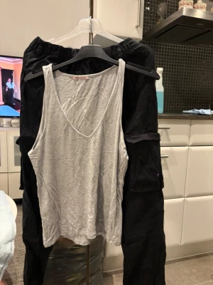 Svarta cargobyxor från F&F - Säljer ett par svarta cargobyxor från F&F med flera praktiska fickor på sidorna. Byxorna har en avslappnad passform och är tillverkade i ett mjukt bomullsmaterial. Perfekta för dig som gillar en streetstyle-look och vill ha bekväma byxor med mycket attityd.