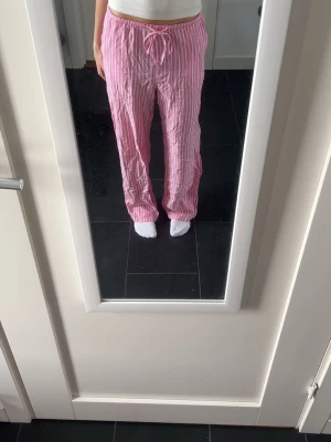Rosa randiga linnebyxor med dragsko - Säljer ett par rosa linnebyxor med vita vertikala ränder och dragsko i midjan. Byxorna har avslappnad passform och raka ben. Oanvända💓
