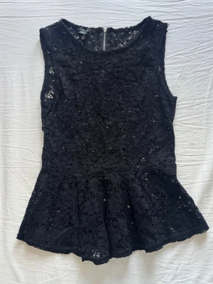 Svart spetspeplum topp - svart ärmlös peplum topp i spets med blommigt mönster. 