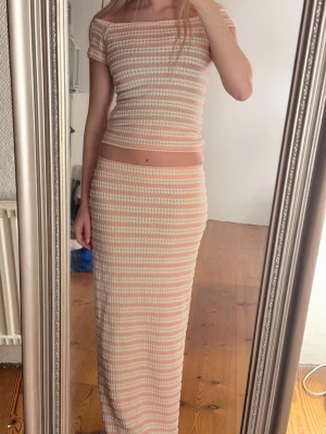 Rosa och vit ribbad topp och kjol  - Säljer en söt ribbad topp och kjol  i rosa och vitt med korta ärmar och rund hals samt lång kjol. 