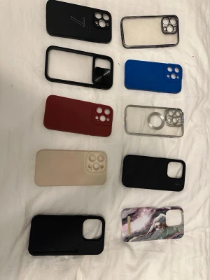 Flera mobilskal i olika färger och material iPhone 14 Pro - Säljer ett paket med tio olika mobilskal för iPhone. Skalen är i färgerna svart, blå, röd, beige, genomskinlig och ett med marmormönster. Materialen varierar mellan plast, silikon och TPU. Några har MagSafe-ring, vissa är genomskinliga och andra har matta eller blanka ytor. Perfekt för dig som vill byta stil ofta.