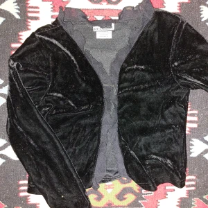 Svart sammetskofta med volangkant - Mjuk sammetskofta från Request med gullig volang