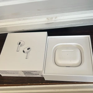 AirPods gen 3 - Apple AirPods 3 med originalförpackning. Trådlösa hörlurar med laddningsetui. Viss smuts synligt på etuiet och insidan, men fungerar som dem ska. Perfekt för dig som vill ha bra ljud och smidig anslutning till Apple-enheter. Funkar som helt nya! Är andvända i 1år. 