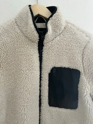  Cremefärgad teddyjacka - Mysig beige teddyjacka! Det är ett hål i fodret inuti i jackan, men kan lätt sys ihop.