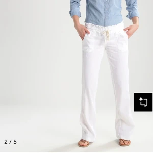 Vita linnebyxor med snörning  - Snygga vita linnebyxor med avslappnad passform och dragsko i midjan. Byxorna går ut längst ner så de blir som en bootcut och de har resår i midjan och praktiska fickor framtill. Perfekta för varma dagar när du vill ha en chill och fräsch look. Ny pris på 600kr.