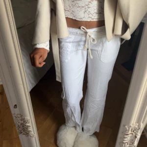 Vita loungebyxor med dragsko - Sitter kort på mig som är 165 cm lång. Säljer ett par vita linnebyxor med avslappnad passform och dragsko i midjan. Byxorna har raka ben och fickor fram, perfekta för en chill och stilren look. Materialet är linneblandning som känns svalt och skönt.