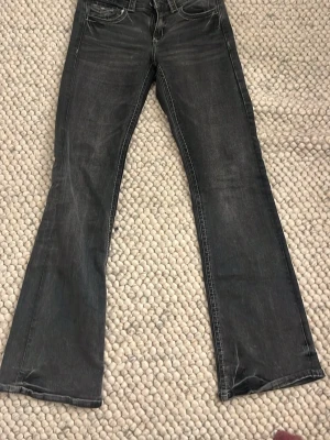Svarta bootcut jeans från Gina Tricot - Säljer ett par svarta bootcut jeans från Gina Tricot. Jeansen har en snygg tvättad look, klassiska fem fickor och normalhög midja. Perfekta för dig som gillar en lite vidare passform nedtill och vill ha en trendig stil.