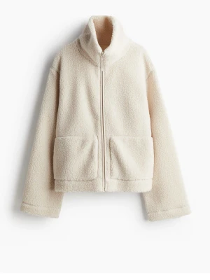 Krämvit teddyjacka med dragkedja - Mysig krämvit teddyjacka med hög krage och dragkedja framtill. Jackan har två stora fickor framtill och är tillverkad i fluffigt teddy-material som ger en avslappnad och trendig look. Perfekt för kyliga dagar och enkel att matcha med olika outfits.