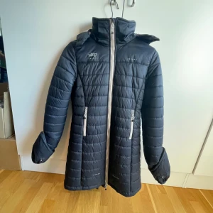 Marinblå lång ridjacka från Uhip ❗️SOLD❗️ - En marinblå ridjacka från uhip i ny skick använd Max 5 gånger,har två dragkedjor, benband och går att öppna i bak, original pris 1795kr 