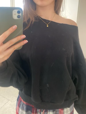 Svart oversized off shoulder sweatshirt - Svart oversized sweatshirt med off shoulder-design och långa ärmar. Tröjan har bred mudd vid ärmslut och nederkant, vilket ger en avslappnad och trendig look.