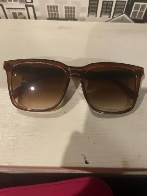 Bruna fyrkantiga solglasögon - Snygga solglasögon med fyrkantiga bågar i transparent brun plast och mörktonade glas. Perfekta för att ge en cool vibe till din outfit. Klassisk och trendig design som passar till många stilar.