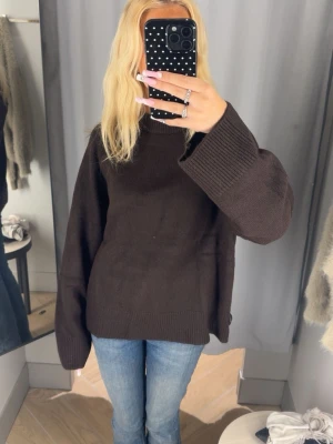 Brun stickad tröja - Mysig brun stickad tröja med oversized passform och breda ärmar. Tröjan har ribbstickade muddar vid ärmslut och är perfekt för lager på lager och en avslappnad stil.