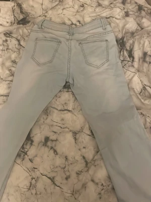Ljusblå bootcut jeans - Säljer ett par ljusblå bootcut jeans med klassiska fem fickor och kontrastsömmar. Jeansen har en låg midja.