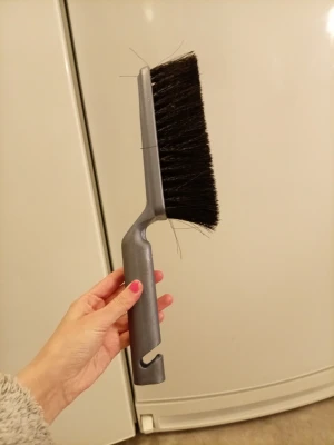 Grå sopborste med svart borst - En praktisk sopborste med grått plastskaft och tätt svart borst. Handtaget har ett hål för enkel upphängning och borsten är rak och bred, perfekt för att sopa upp smulor eller damm. Passar bra till städning i hemmet eller på kontoret.