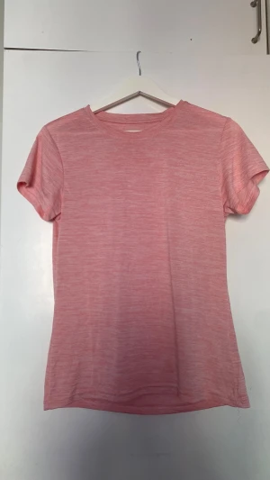 Ljusrosa t-shirt från Biltema - En enkel och stilren ljusrosa t-shirt från Biltema i 100% polyester. T-shirten har rund halsringning och korta ärmar. Perfekt för dig som gillar en basic look med en mjuk och lätt känsla.