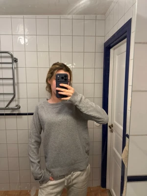 Grå stickad tröja från Vero Moda - Mysig grå stickad tröja från Vero Moda i enkel design. Tröjan har rund halsringning, långa ärmar och ribbade muddar vid ärmslut och nederkant. Perfekt basplagg för lager på lager och chill dagar.