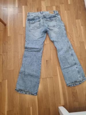 Ljusblå utsvängda jeans med vintagekänsla - Säljer ett par ljusblå jeans från gina tricot med rak passform och klassiska fem fickor. Jeansen har en avslappnad look och är tillverkade i slitstark denim. Perfekta för dig som gillar en retrostil och vill ha ett par bekväma jeans till vardags.