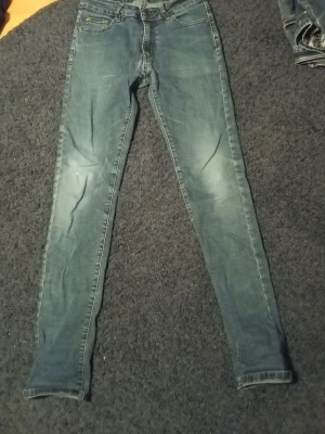 Blå jeans slim Armani - Snygga blå jeans med lätt slitning och smal passform. Jeansen har klassiska fem fickor, dragkedjegylf och är tillverkade i ett stretchigt material för extra komfort. Perfekta för en trendig och avslappnad stil.