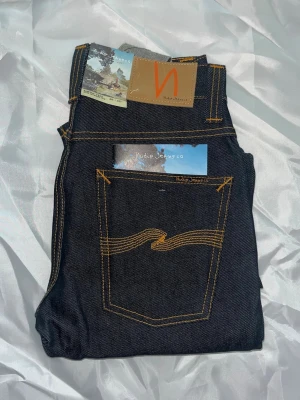 Nudie jeans grim tim - Helt nya! Nudie jeans i modellen Grim Tim. Midja 33cm, längd 106cm. Tyvärr så har jag ingen bild när jag bär jeansen på.  för bättre inblick i passformen rekommenderar jag att googla på modellnamnet. För storleksguide kolla måtten noggrant då jeansen alltid kan vara uppsydda heller krympta och jag ej tar emot returer :) 