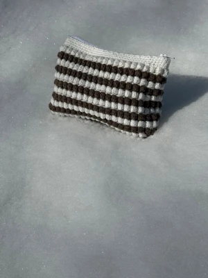 Randig virkad necessär med dragkedja - Handgjord virkad necessär i vita och bruna ränder. Perfekt för småsaker eller smink. 