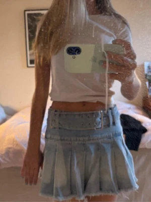 Zara jeanskjol - Trendig ljusblå jeanskjol med plisserad design och rå kant nertill. Kjolen har ett matchande brett bälte med silverdetaljer som ger en cool vibe. Perfekt för dig som gillar en avslappnad men ändå stilsäker look.