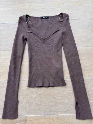 Brun långärmad topp - Snygg brun ribbad topp från Gina Tricot med långa ärmar och en liten slits vid båda ärm sluten. Toppen är i ett väldigt mjukt och skönt material. Toppen är aldrig använd endast testad en gång. 