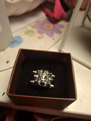 Silvrig ring från edblad - Cool silvrig ring med ett chunky, bred design. Ringen har en futuristisk känsla med sina geometriska former och metalliska yta. Perfekt för dig som gillar statement-smycken och vill sticka ut.