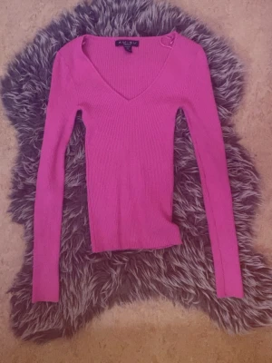 Stark Rosa ribbad tröja med v-ringning - Stark rosa långärmad tröja från Amisu/newyorker med ribbad struktur och djup v-ringning. Perfekt för dig som gillar färg och vill ha en smickrande passform. Materialet är stretchigt och mjukt, vilket gör den bekväm att bära hela dagen.