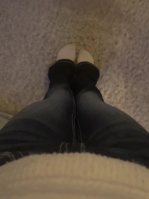 Mörkblå bootcut jeans - Säljer ett par mörkblå bootcut jeans med vita kontrastsömmar och klassisk femficksdesign. Jeansen har en lätt tvättad look och sitter tajt över låren för att sedan bli vidare nedtill. Är även lite trasiga längst ner vid fötterna men jätte fina ändå. Perfekta för dig som gillar en avslappnad men trendig stil.