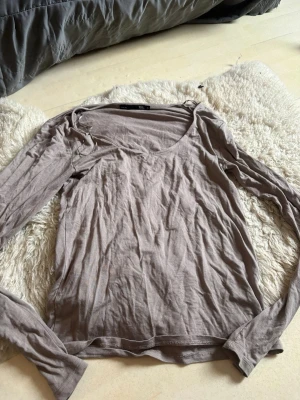 Beige långärmad topp med v-ringning - En enkel beige långärmad topp med v-ringning och smal passform. Tillverkad i mjukt bomullsmaterial, perfekt för lager på lager eller att bära som den är. Stilren och lättmatchad färg som funkar till det mesta.