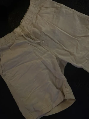 Beige shorts med resår och snörning - Snygga beige shorts med elastisk midja och snörning. Shortsen har två sidofickor fram och två bakfickor. Perfekta för varma dagar och har en avslappnad passform.