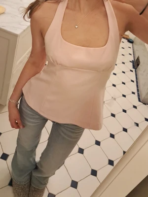 Ljusrosa halterneck topp med rosetter - Supersöt ljusrosa halterneck topp med öppen rygg och två rosetter i ryggen💕 köpt för ett tag sedan men är i nyskick! aldrig använd. 