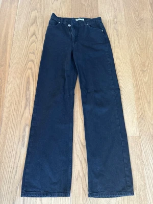 Svarta raka jeans wide leg från pull & bear - Snygga svarta jeans med rak passform / vida ben. Klassisk femficksmodell och knappgylf. Perfekta till en avslappnad stil och funkar året runt. Materialet är kraftig denim som ger en tidlös look.