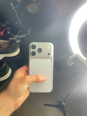 Vit iPhone med trippelkamera - Snygg vit iPhone med stilren design och rundade hörn. Baksidan har tre stora kameralinser och en blixt, vilket ger grymma fotomöjligheter. Tillverkad i glas och metall för en premiumkänsla. Perfekt för dig som gillar Apple och vill ha en modern smartphone.