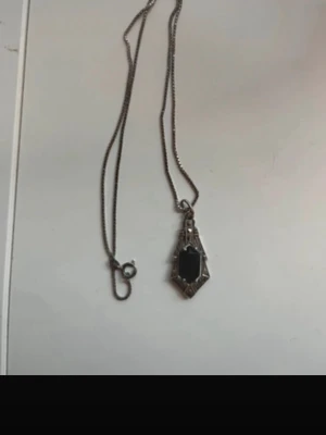 Silverhalsband och armband med mörkblå sten - Snyggt halsband i silver med en geometrisk, vintageinspirerad berlock. Berlocken har en svart, rektangulär sten infattad i en detaljerad ram. Kedjan är tunn och stilren, perfekt för att ge din outfit en cool touch. Armbandet hör till och följer med på köpet. Håller på att betala av saker så är tacksam för varje krona. 🙏