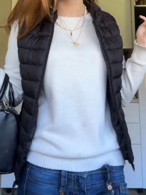 Svart dunväst med quiltad design - Snygg svart dunväst med quiltad look och hög krage. dragkedja framtill. Perfekt att slänga över en hoodie eller tröja för extra värme. Enkel och stilren design som passar till det mesta.