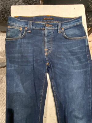Mörkblå Nudie Jeans - Ett par riktigt snygga nudie jeans. Knappt använda och sitter riktigt bra, säljer pågrund av att de inte passar mig längre. För mer frågor skriv gärna!