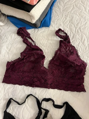 Vinröd spets-bh med breda axelband - Vinröd bh i spets med breda axelband och v-ringad skärning. Bh:n har fina spetsdetaljer och är helt utan vaddering, vilket ger en naturlig look. Perfekt för dig som gillar mjuka och bekväma underkläder med snygg design.