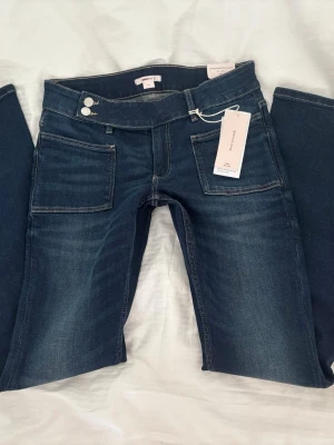 Lågmidjade Blå jeans - Säljer ett par Lågmidjade blå jeans från Gina Young med cool design. Helt nya med prislapp på. Midja: 38cm (stretchiga). Innerben: 82cm