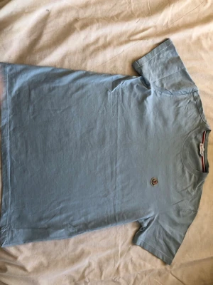 Ljusblå Moncler t-shirt i bomull - Snygg ljusblå t-shirt från Moncler med klassisk rund hals och korta ärmar. Tillverkad i mjuk bomull och pryds av Monclers ikoniska logotyp på bröstet. Perfekt basplagg för en clean och stilren look.