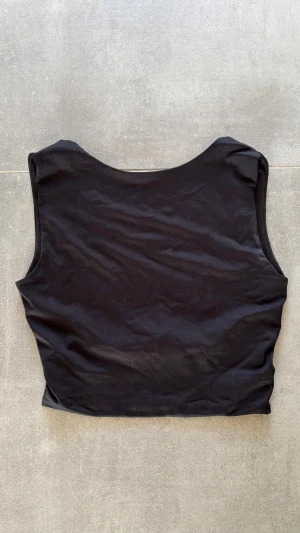 Svart croppad topp med öppen rygg - Säljer en svart croppad topp med öppen rygg i stretchigt material från New Yorker. Aldrig använd och storlek xs.❤️