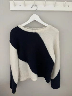  stickad tröja  - Säljer en stickad tröja i svart och vitt med ett coolt vågmönster. Tröjan har rund halsringning, långa ärmar och är gjord i ett mjukt, fluffigt material. Perfekt för dig som gillar en unik och trendig look.