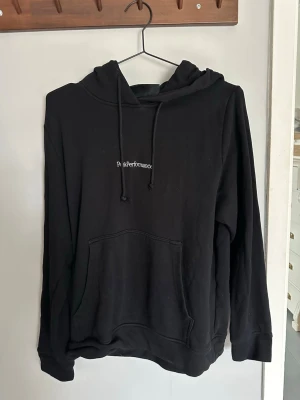 Svart hoodie från Peak Performance - Svart hoodie från Peak Performance med klassisk huva och dragsnören. 
